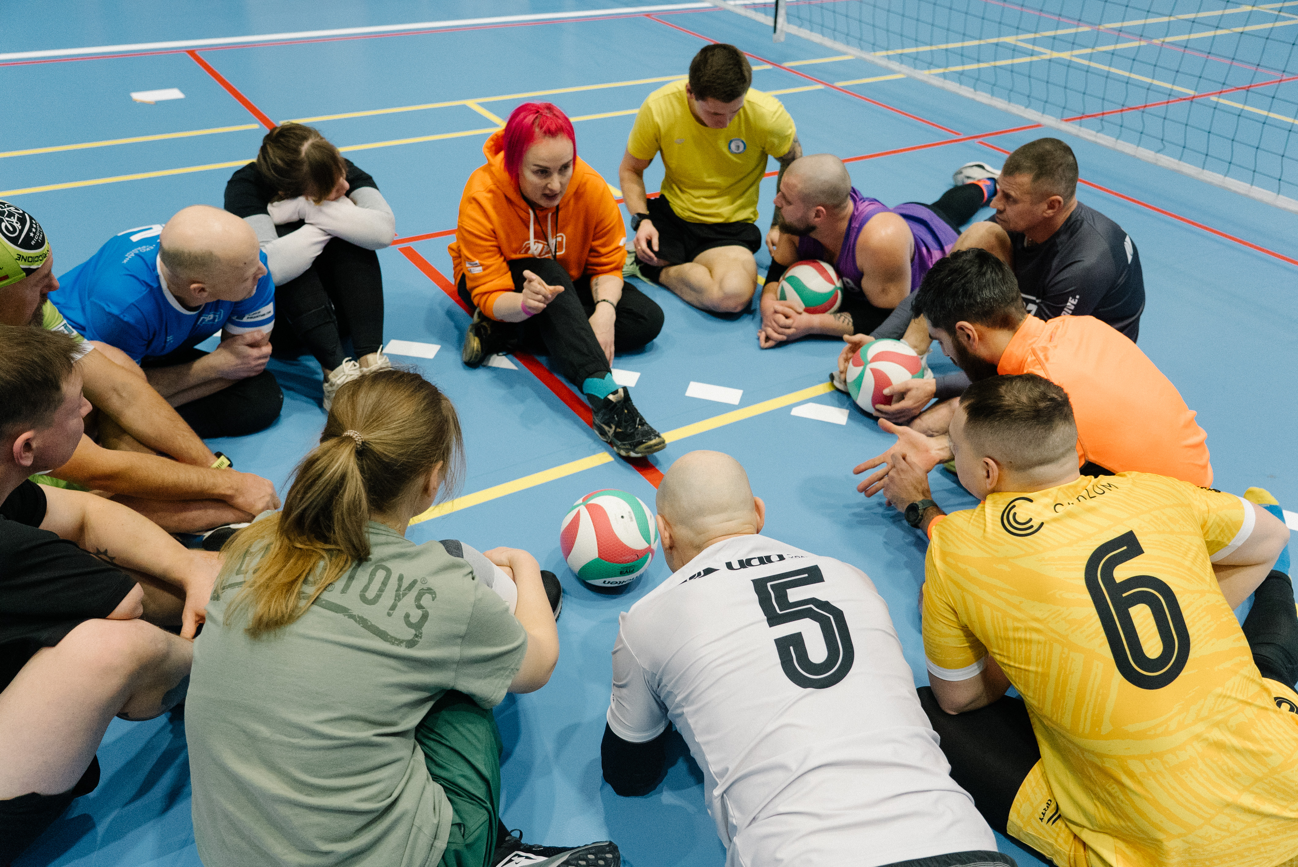 Учасники спілкуються з тренеркою з волейболу сидячи